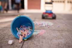 Sidewalk chalk spills from a bucket in this family documentary photography picture