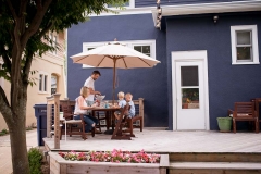 Family dines on deck during a family day in the life photojournalism session near Grand Rapids