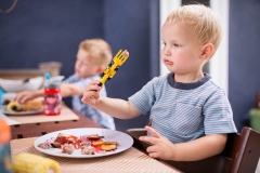 Boys eat dinner at backyard table as a Grand Rapids photographer captures their documentary family session