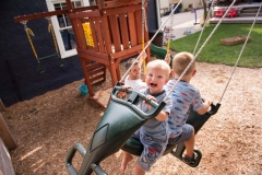 Two boys swing and laugh during a Grand Rapids day in the life family documentary session