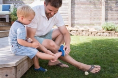 Son watches attentively while father ties his shoes during East Grand Rapids family session