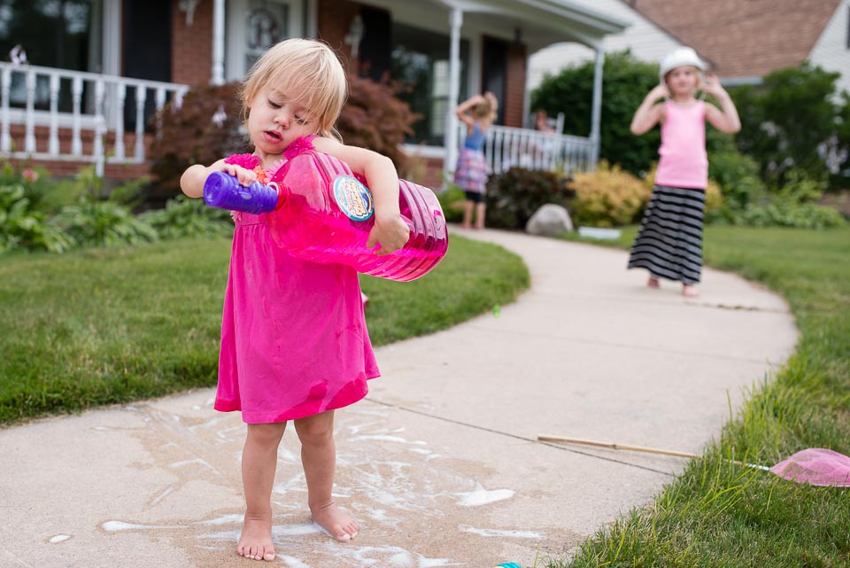 Grand Rapids family documentary image of young child spilling bubble solution while filling a smaller container