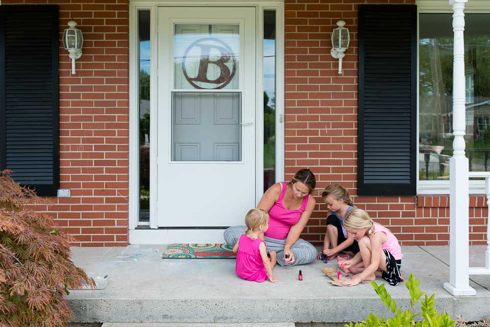 Mother and girls paint their nails on a Grand Rapids porch during family documentary session