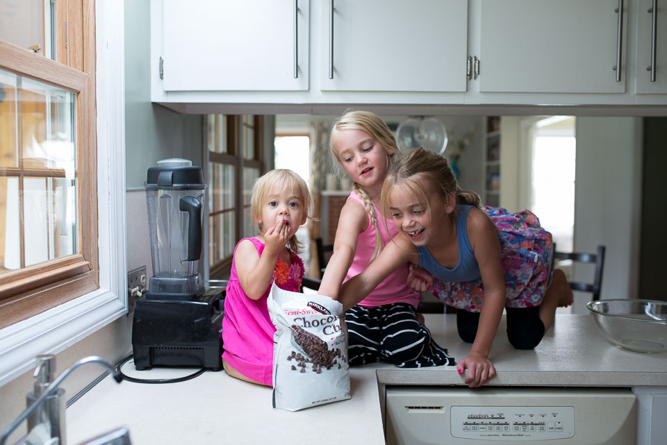 Girls sneak chocolate chips in this image by a Grand Rapids family documentary photographer