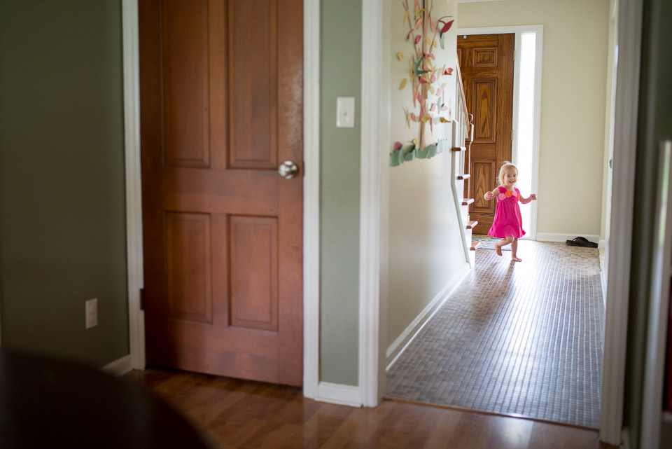Young child runs through the house during a family documentary photography session near Grand Rapids
