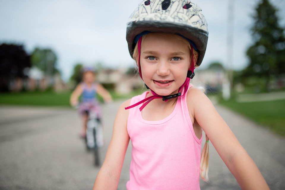 Girl wearing a bike helmet gazes into camera during Grand Rapids day in the life session