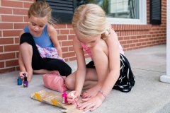 Sisters paint their nails on the porch in this documentary family photograph near Grand Rapids