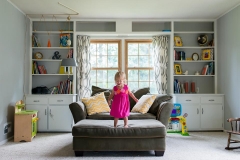 Girl stands poised to jump from couch in Grand Rapids documentary family photography session