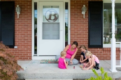 Mother and girls paint their nails on a Grand Rapids porch during family documentary session