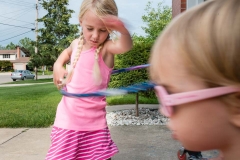 Girl hula hoops and her sister wears sunglasses during a documentary family session near Grand Rapids