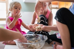 Cookie dough dangles from a child's fingers in the Grand Rapids family documentary photograph