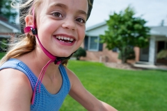 Girl grins as she rides her bike past the family documentary photographer