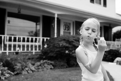 Black and white image of a child blowing bubbles during a family documentary session