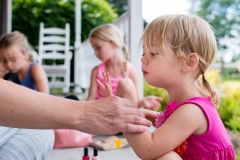 Child blows on her nails to dry them during a documentary family session in West Michigan.