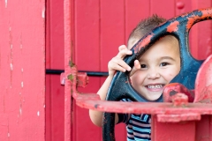 A boy looks through the wheel of a caboose in this Rockford Michigan child portrait