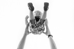 A West Michigan father tosses his laughing son into the air for a creative child portrait