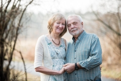 An elderly couple embraces and smiles in this anniversary portrait