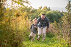 Dad chases a laughing boy at Roselle Park in Ada