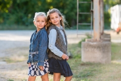 Sisters pose leaning back to back in urban Grand Rapids