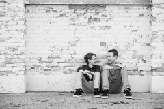 Tween boys laugh together while seated against an urban brick wall in Grand Rapids