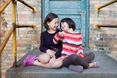 Children giggle at each other in this urban Grand Rapids family portrait