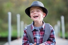 A boy wears a dapper hat and laughs in a portrait at Blandford Nature Center