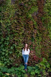 Grand Rapids senior portrait of smiling girl posed by ivy wall