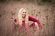 Senior picture of a senior girl in a red dress in a fall field near Grand Rapids
