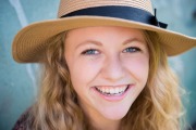 Senior girl wearing a straw hat smiles in an urban Grand Rapids senior picture