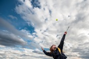 Tennis player leaps in front of dramatic clouds for her senior pictures in Grand Rapids
