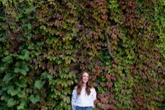 Grand Rapids senior portrait of smiling girl posed by ivy wall