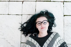 Senior girl lays on cobblestones for downtown Grand Rapids senior pictures