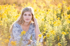 Yellow flowers surround a Grand Rapids senior girl in her senior portrait