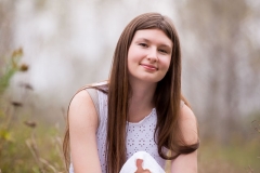 Senior girl poses in a natural setting for portraits near Grand Rapids