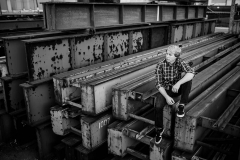 A senior guy poses on steel beams for an urban Grand Rapids senior portrait