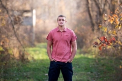 Boy poses in a natural West Michigan field for male high school senior portraits