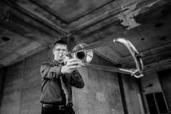 Trombone musician poses for creative male high school senior portraits in downtown Grand Rapids