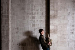 Male saxophone musician poses for creative artistic high school senior portraits in Grand Rapids