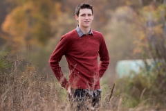 Senior Grand Rapids boy poses for male senior pictures in a fall field near Grand Rapids