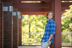 Male high school senior guy leans against a post in Grand Rapids