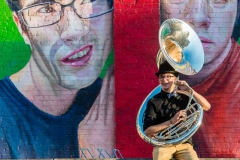 Male musician poses in front of a mural with his sousaphone for urban Grand Rapids senior portraits