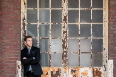 Urban windows behind a well dressed high school senior guy in downtown Grand Rapids senior pictures