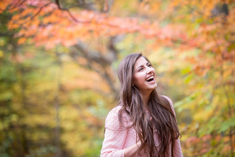 Grand Rapids senior portrait photographer captured a senior girl laughing surrounded by Michigan fall color